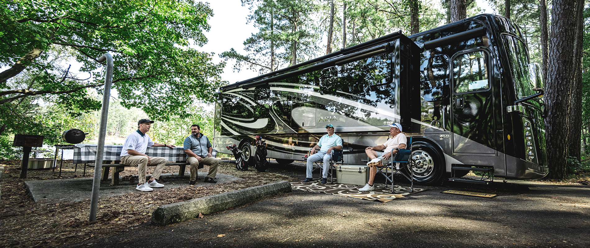 Thor motor coach parked at a camp site with friends having a conversation while grilling food