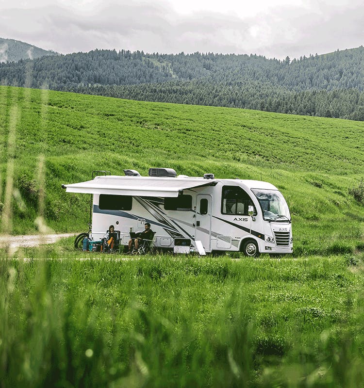 2024  Axis Class A Motorhome in open grassy area with woods and mountains behind