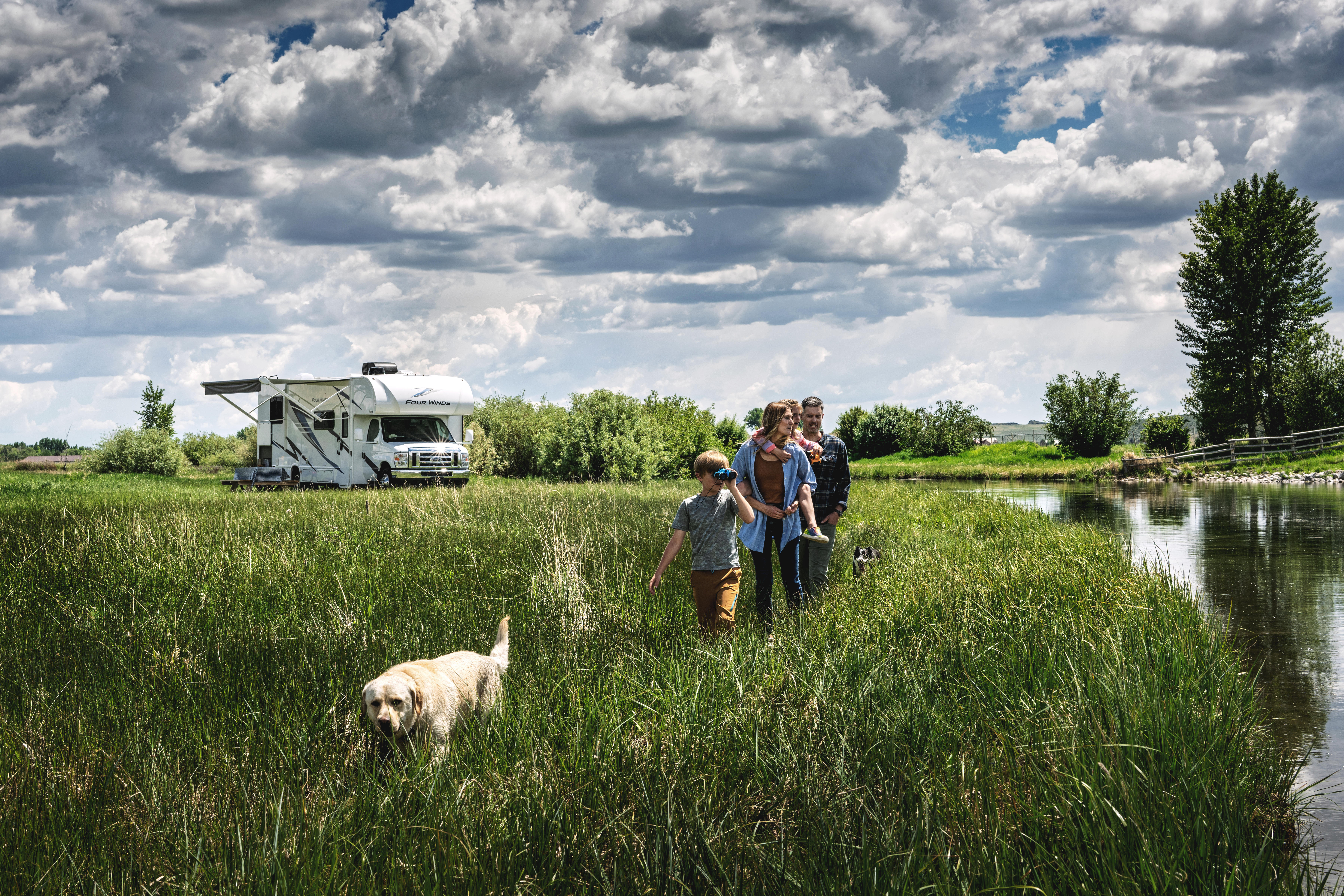 Four Winds parked in beautiful scenery with family and dog walking