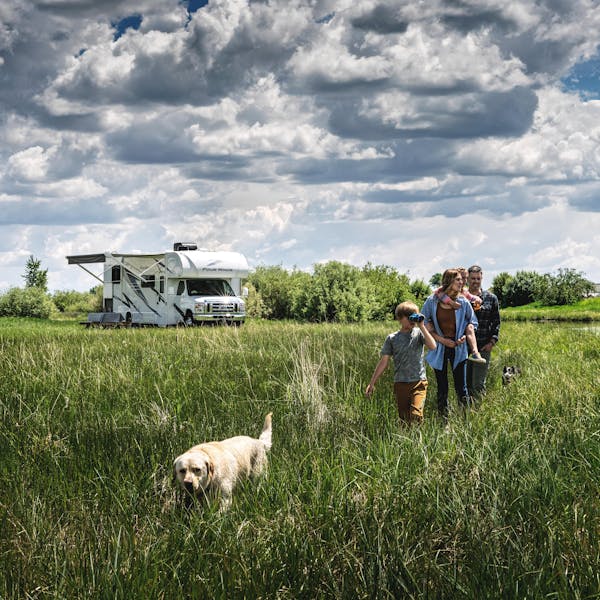 Four Winds parked in beautiful scenery with family and dog walking