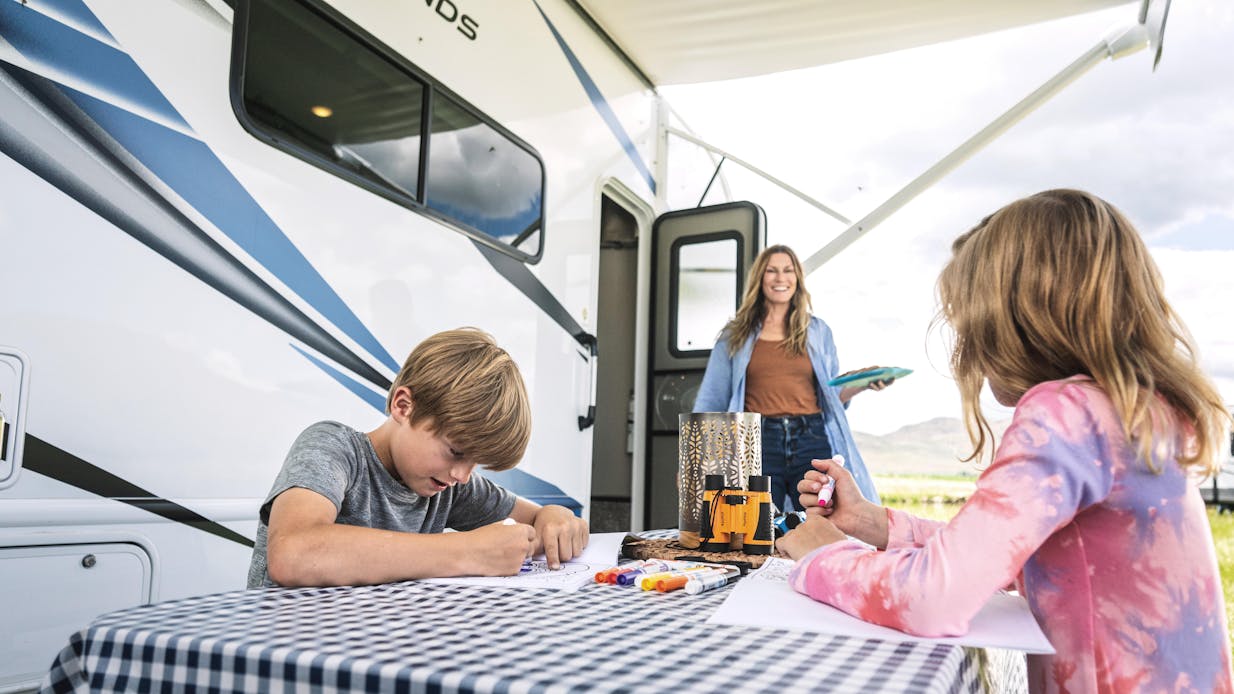 Four Winds power patio awning with family having fun outside