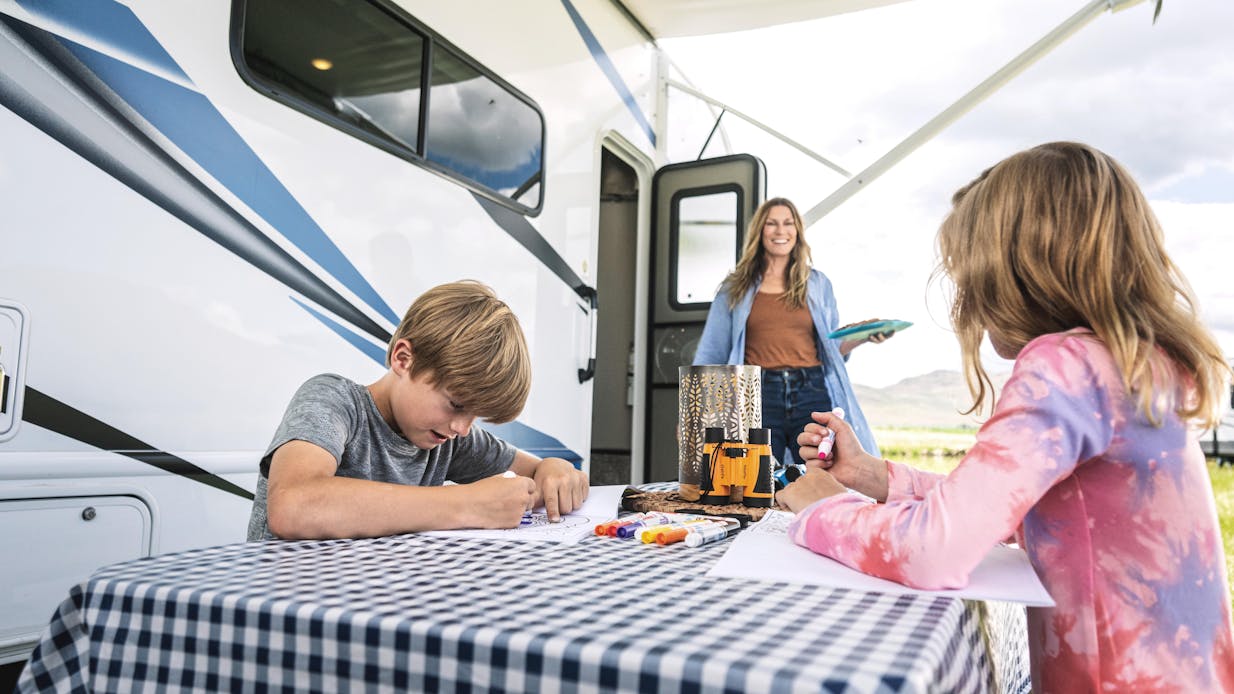 Four Winds power patio awning with family having fun outside