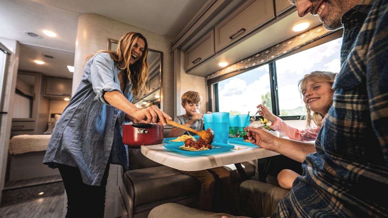 Four Winds class C rv interior with family sitting around dinette booth