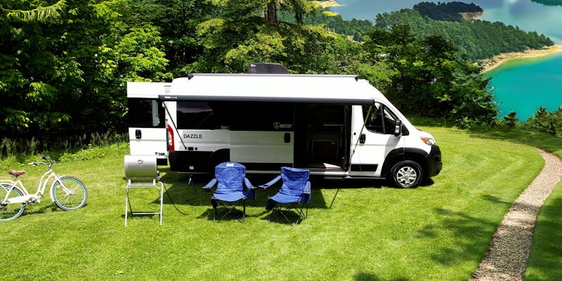 Dazzle camper ban in front of scenic lake and tree