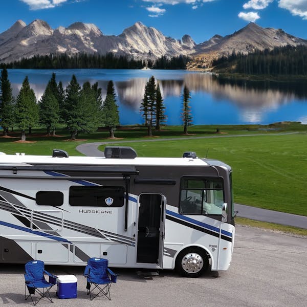 Hurricane motorhome at campsite in front of reflective lake and stunning mountain view