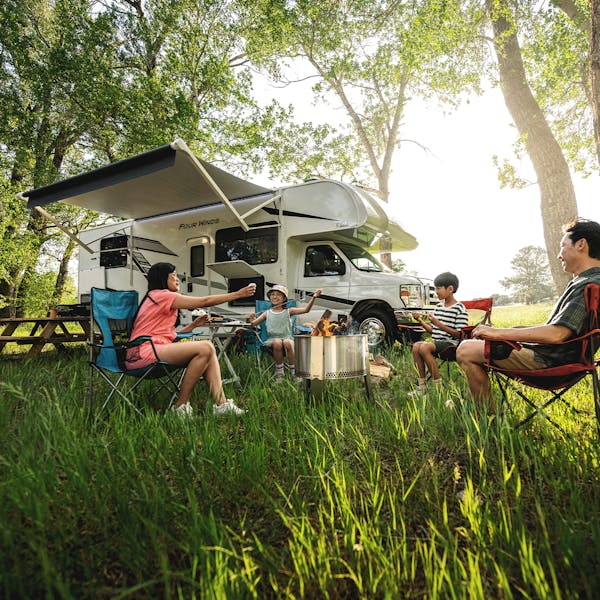 Family resting outside of Class C RV on sunny day