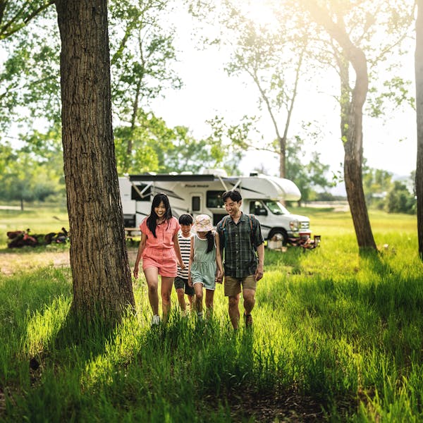 Family walking in woods in front of motorhome