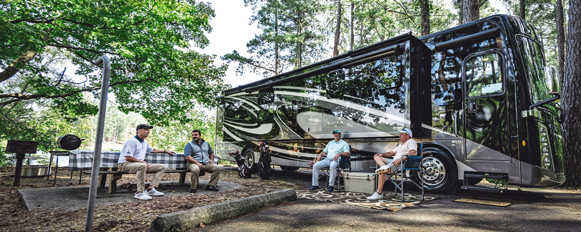 2021 Thor Aria Class A Diesel Motorhome Lifestyle corporate photo shoot men in chairs sitting outside of Aria