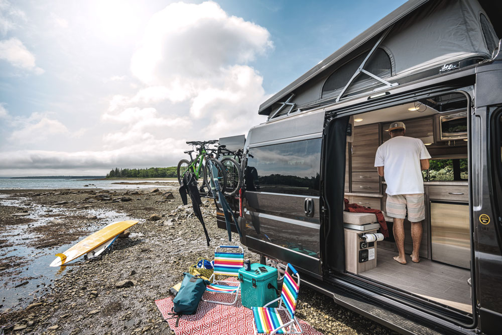 2022 Thor Scope Class B RV Camper Van Lifestyle Maine Corporate photo shoot Thule bike rack on rear door with entry door open and SkyBunk® Sky Bunk Pop Top extended key feature