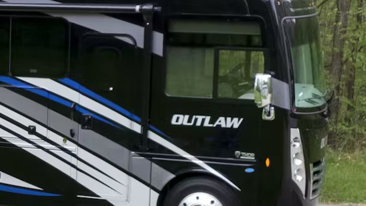 Outlaw Class A $10,000 rebate with campground setup and blue jeep