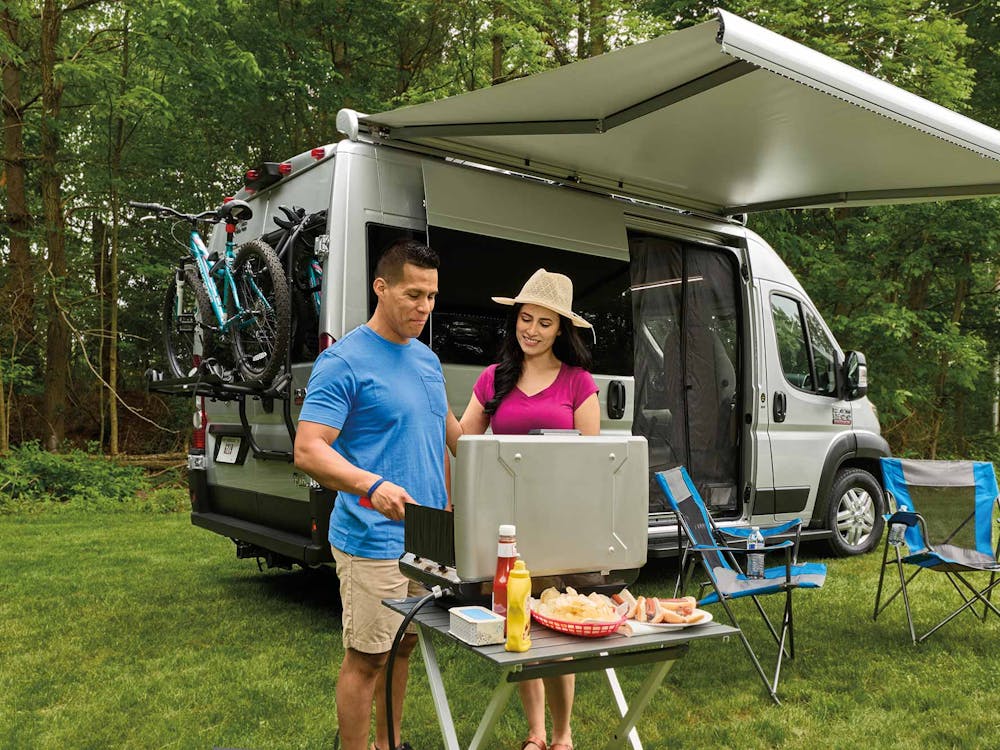 2022 Thor Rize Class B RV Camper Van Lifestyle couple grilling together with Thule® bike rack on rear door